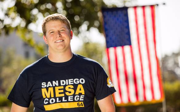 Calvin Dixon stands proudly, donning his San Diego Mesa College t-shirt in front of the American flag. 